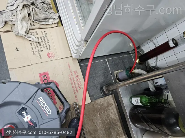 식당 주방 바닥에 놓인 세척 장비와 호스