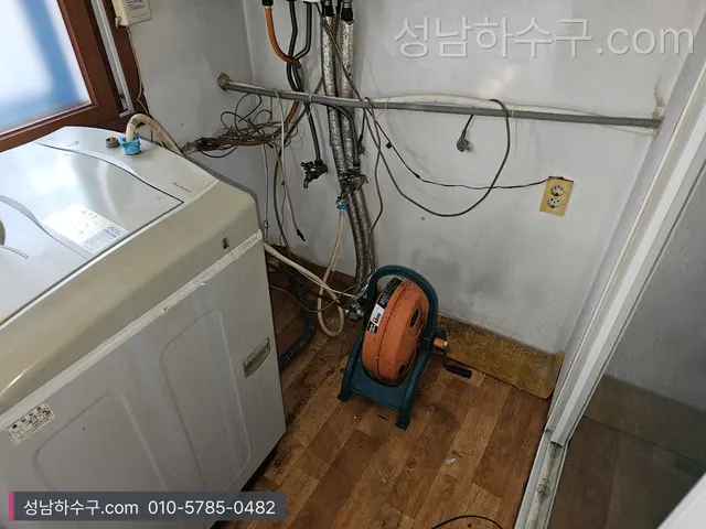 세탁기 옆 바닥에 놓인 스프링 장비 릴